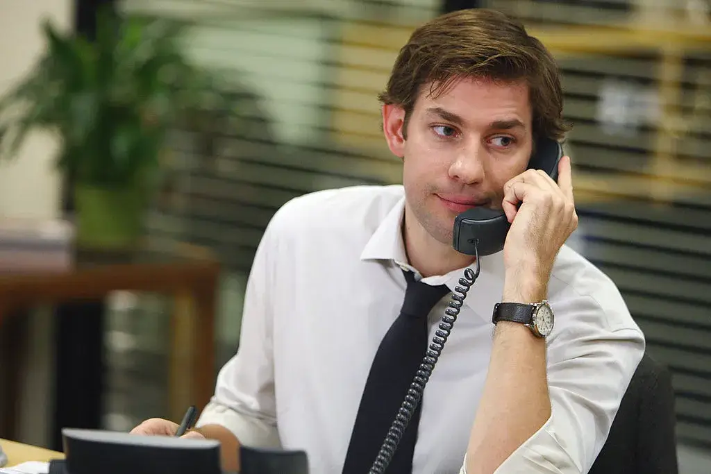 Personagem Jim do seriado "The office" fazendo uma venda no 1 a 1 pelo telefone.